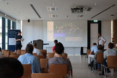 A seminar with participants, a presentation screen, and a speaker who presents material to the group.